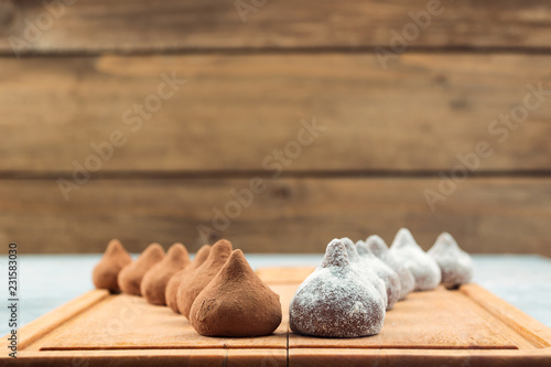 Chocolate truffles, sprinkled with cocoa powder and powdered sugar, located on the kitchen wooden Board in two rows, copy space.