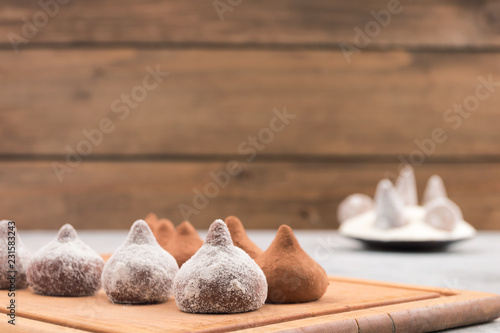 Chocolate truffles covered with white powdered sugar on a background of chocolates in cocoa powder, copy space.