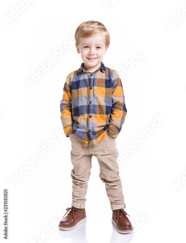 Cute little boy posing with the hands in his pockets, isolated over white background