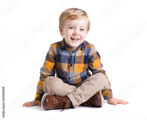 Adorable little kid seated on the floor, isolated over white bacground