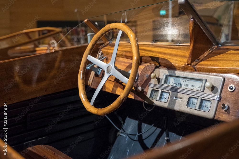 A view of the steering wheel and dashboard of an antique vintage wooden motor boat.