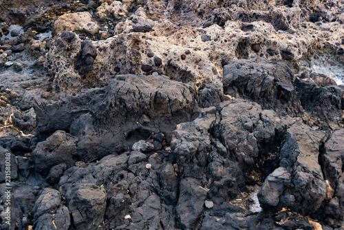 hardened black lava with patches partially polished by ocean waves