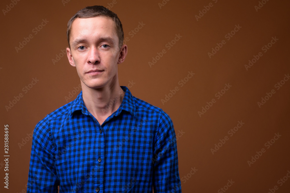 Studio shot of young man against brown background Studio shot of young man against brown background
