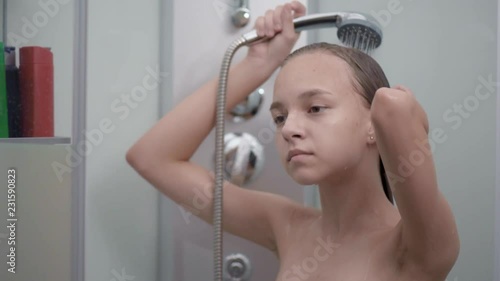 Smiling young girl bathing under a shower at home. Beautiful teen girl taking shower and washing in the bathroom. Happy child washing head, face and body with water. Stock Video | Adobe Stock 