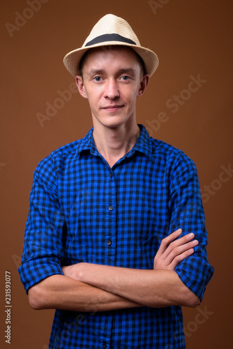 Studio shot of young tourist man against brown background