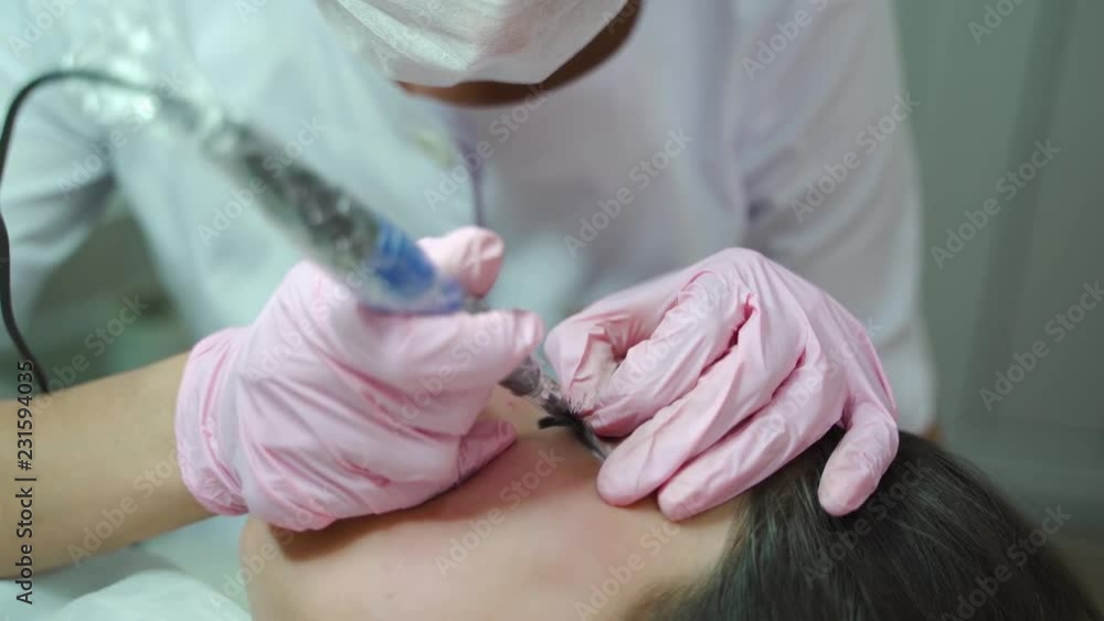 a beautician in gloves is working with the using of professional equipment in a beauty salon. The procedure of permanent makeup of eyes for women. a beautician in gloves is working with the using of professional equipment in a beauty salon. The procedure of permanent makeup of eyes for women.