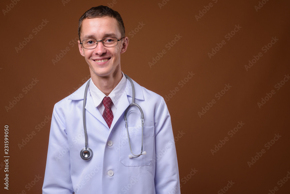 Studio shot of young man doctor against brown background Studio shot of young man doctor against brown background