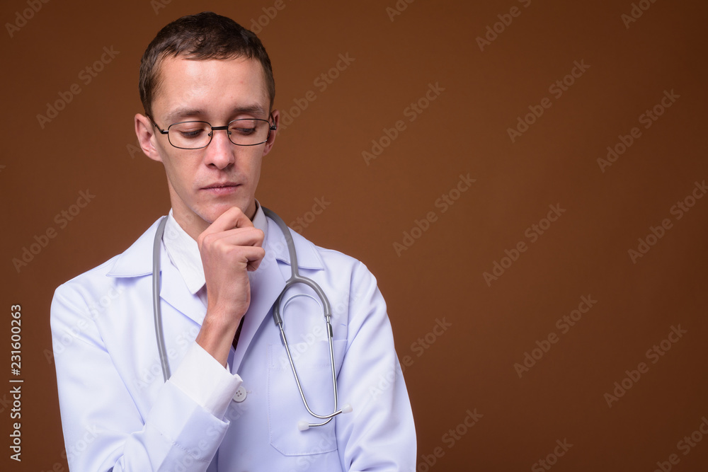 Studio shot of young man doctor against brown background Studio shot of young man doctor against brown background