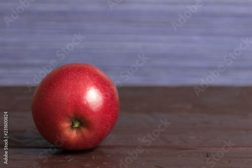 Isolated red mcintosh apple on wooden surface with purple background 