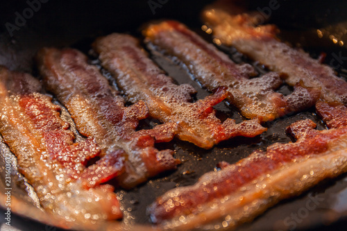 Fotografie Bacon strips or rashers cooked in frying pan in the rays of sunlight