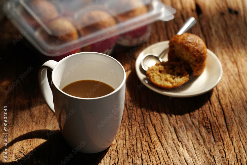 Hot coffee on wooden table, The best instant coffee served with banana cake. Porcelain coffee cup on table with dessert, Selective focus and free space for text. Industrial food and drink concept. Hot coffee on wooden table, The best instant coffee served with banana cake. Porcelain coffee cup on table with dessert, Selective focus and free space for text. Industrial food and drink concept.