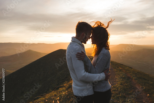 Happy couple hugging and kissing at sunset witn amazing mountain view фототапет