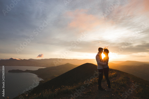 Fotografia Happy couple hugging and kissing at sunset witn amazing mountain view