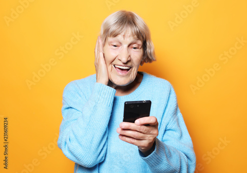 lifestyle, tehnology and people concept: old granny looks at her smart phone and is surprised