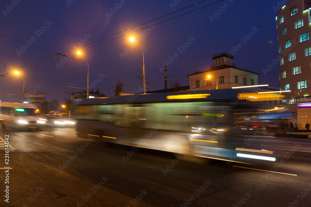The motion of a blurred bus on the avenue in the evening.