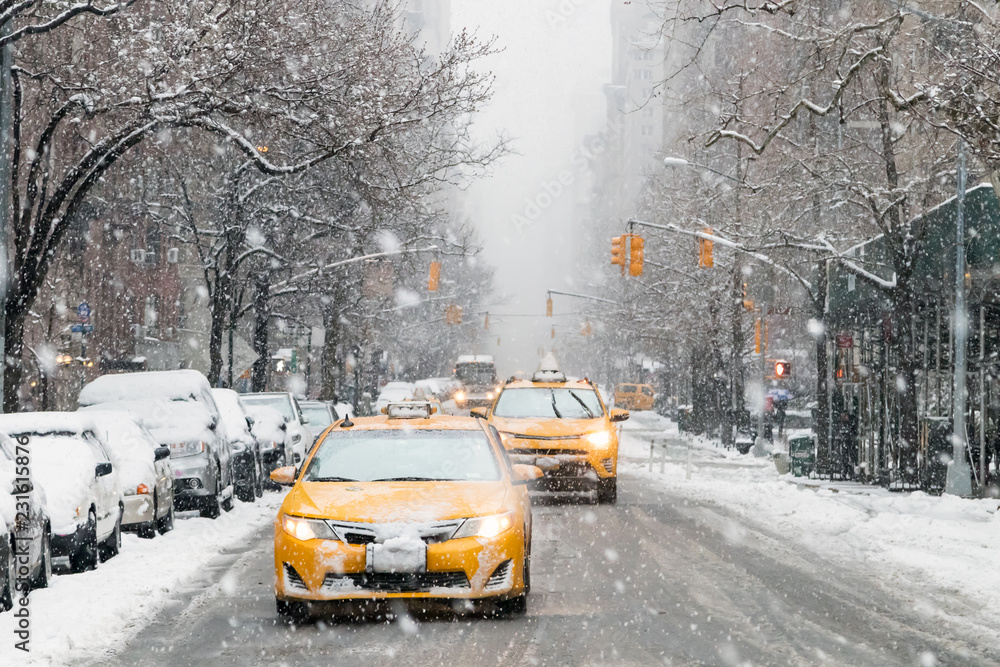 Taxis drive down a snow covered 5th Avenue during a winter nor'easter storm in New York City - obrazy, fototapety, plakaty 
