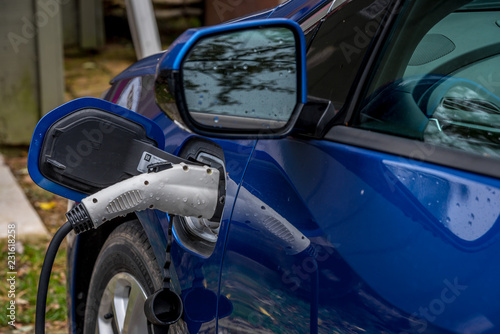 Blue electric car charging at a rural charging station © tamas
