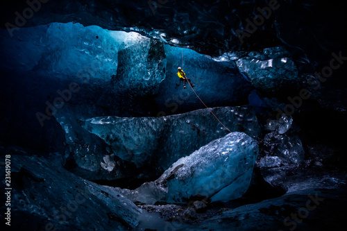 Obraz na plátně Ice climber abseiling into massive cavern in ice cave
