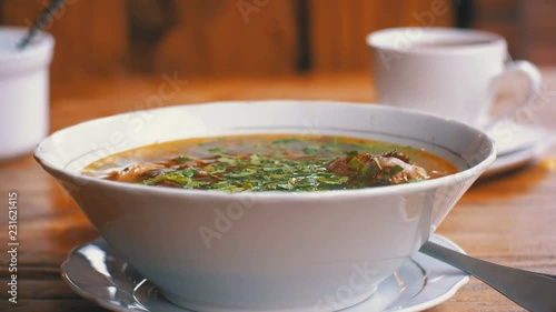 Plate of Georgian Traditional Khashlama Soup with Meat and Greens on a Wooden Table in a Restaurant. Close-up. Georgian cuisine. photo