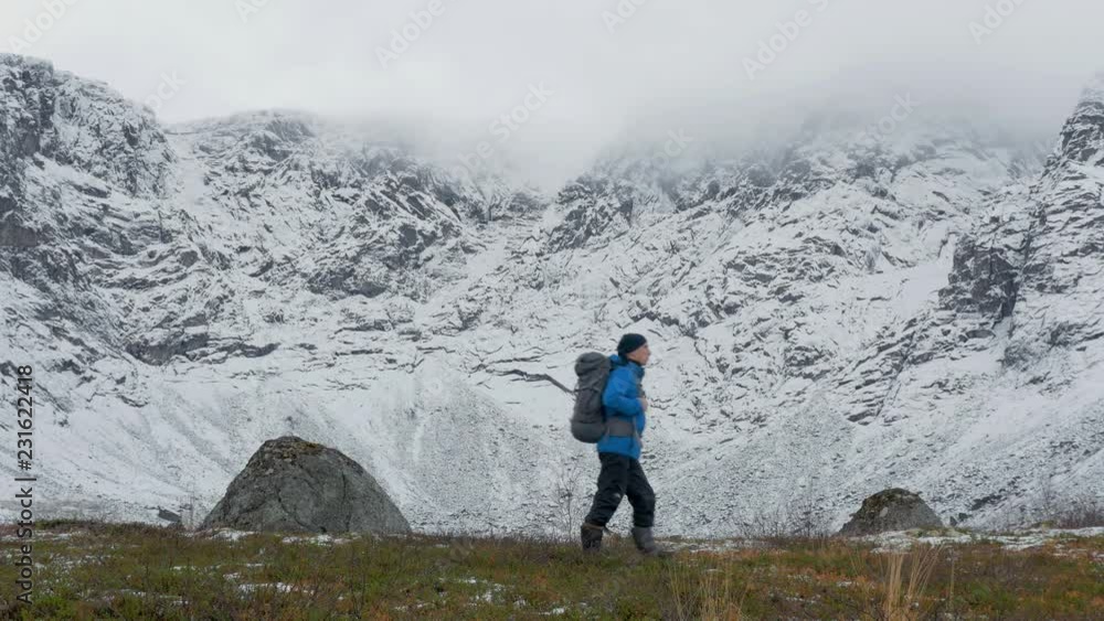 A man with a backpack, alone, traveling in the mountains. It he goes along high snowy peaks. A man with a backpack, alone, traveling in the mountains. It he goes along high snowy peaks.