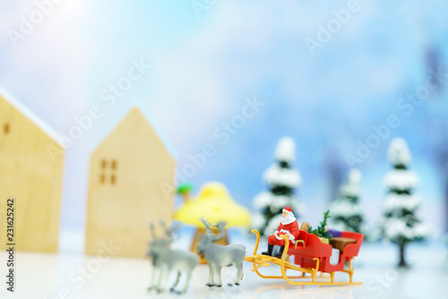 Miniature people  Santa Claus sitting Reindeer Sleigh with greeting or postal card and christmas tree. Christmas and Happy New Year concept.