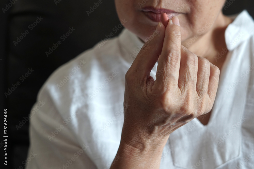 elderly woman are eating medicine and with pills and glass of water at home elderly woman are eating medicine and with pills and glass of water at home