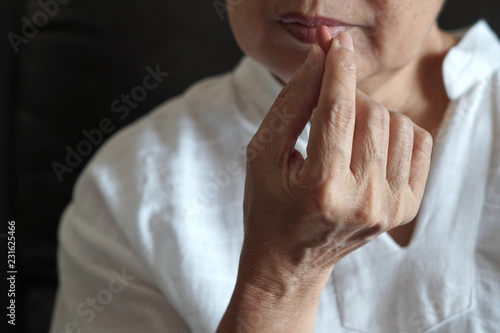 elderly woman are eating medicine and with pills and glass of water at home