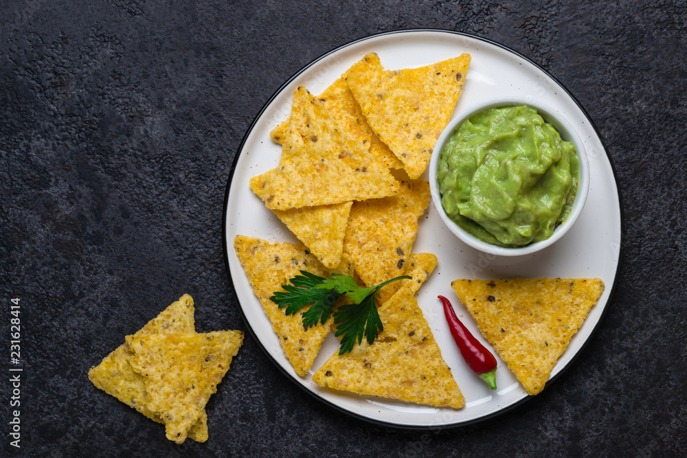 Traditional Latinamerican Guacamole With Corn Chips Nachos on black background Traditional Latinamerican Guacamole With Corn Chips Nachos on black background