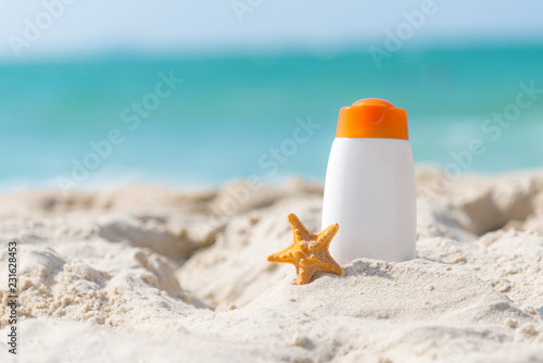 Protective sunscreen or sunblock and sunbath lotion in white plastic bottles with sandals on tropical beach, summer accessories in holiday, copy space.  Summer Concept
