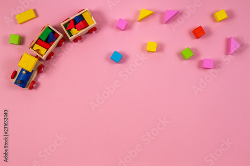Toy background. Wooden toy train with colorful cubes on pink background