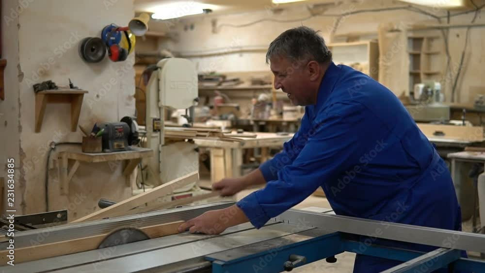 Carpenter at work at his workshop, wood processing on a woodworking machine Carpenter at work at his workshop, wood processing on a woodworking machine