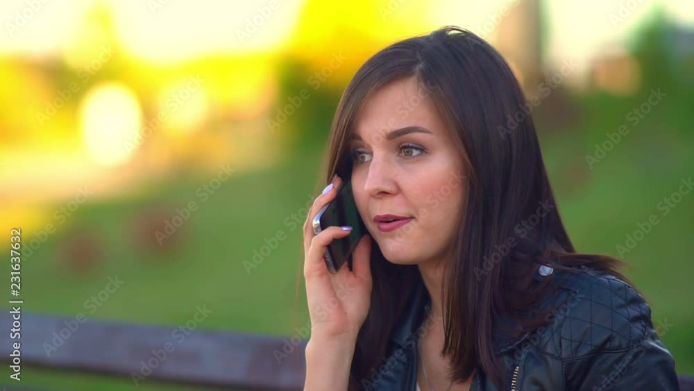Girl in the Park, talking on the phone. Puts down the phone, begins to eat a bun. Girl in the Park, talking on the phone. Puts down the phone, begins to eat a bun.
