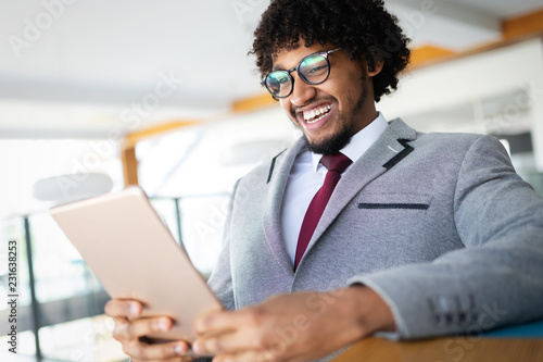 Handsome afro american businessman in classic suit is using a digital tablet