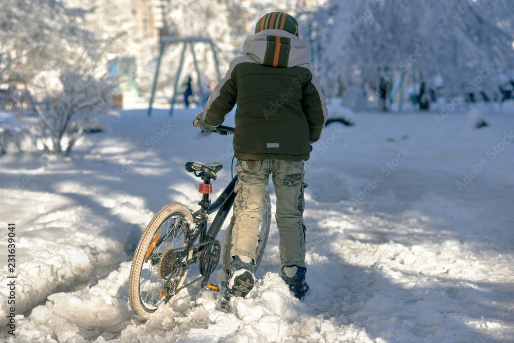 Back view of teenager boy with winter bike on street