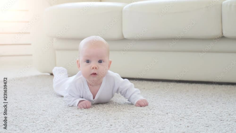 Concept of children and parenthood. Cute Happy Baby is Lying on Carpet Concept of children and parenthood. Cute Happy Baby is Lying on Carpet