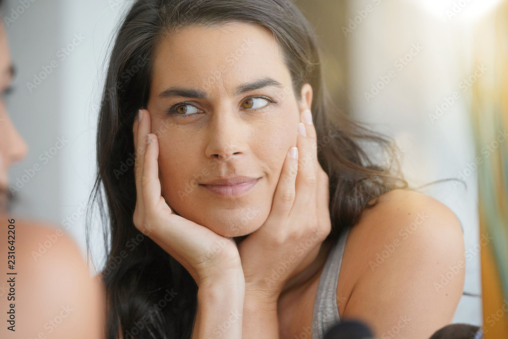 Beautiful woman in front of mirror looking at her face Beautiful woman in front of mirror looking at her face