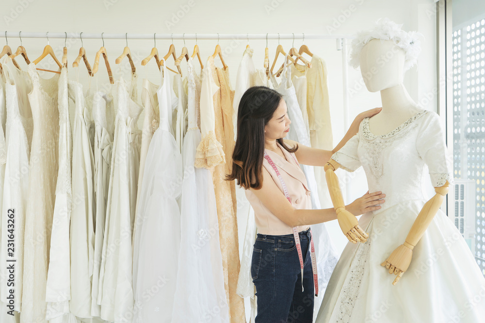 Asian woman tailor or sales assistant or designer wedding dresses in bridal wear store or boutique
