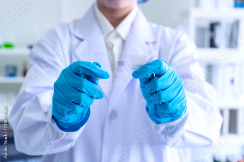 Foto hand of scientist or student or Young female researcher with microscope slide while working on forensic laboratory microscope