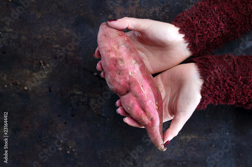  Batat. Kobieta trzyma w dłoniach słodki ziemniak.