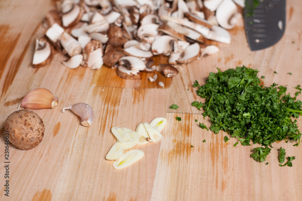 Chopped champignons, parsley and garlic on wooden surface Chopped champignons, parsley and garlic on wooden surface