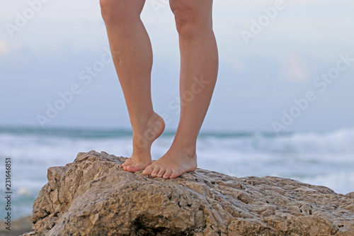 girl's legs against the background of the sea and the sand