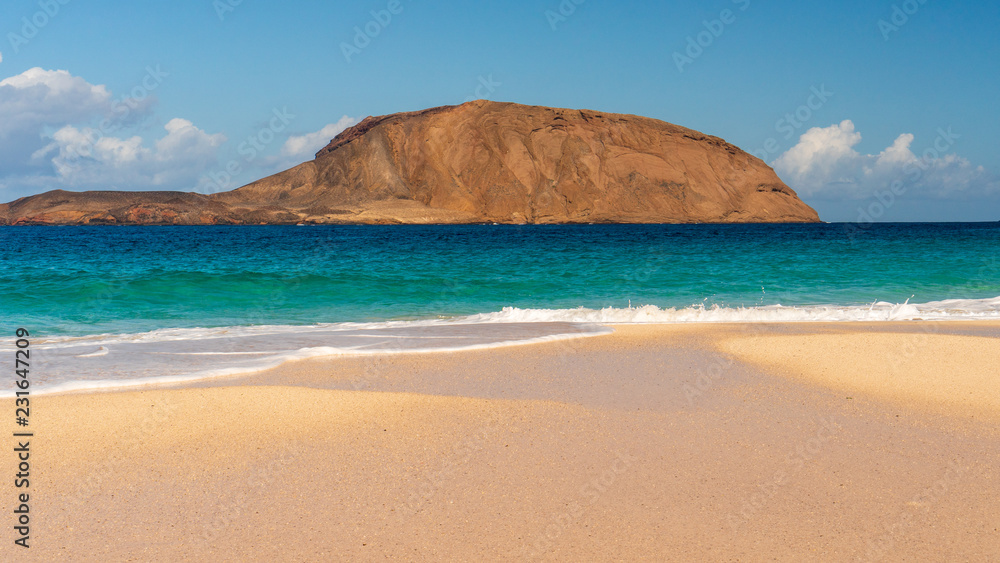 Golden sand beach landscape with turquoise waters on a volcanic island.  Playa de la Conchas on La Graciosa Island, Canary, Spain.