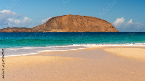 Golden sand beach landscape with turquoise waters on a volcanic island. Playa de la Conchas on La Graciosa Island, Canary, Spain.