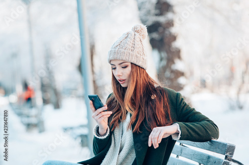 Young  woman smiling with smart phone and winter landscape .