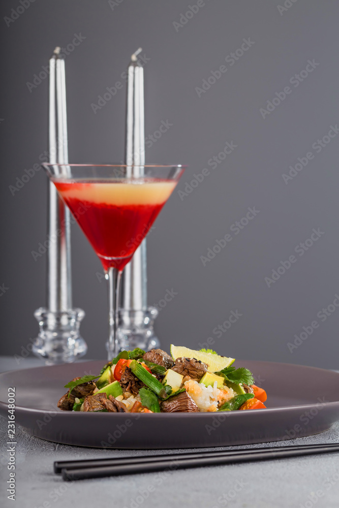 Poke with beef and rice on a beautiful plate with candles and a glass of drink. Hawaiian cuisine. Poke with beef and rice on a beautiful plate with candles and a glass of drink. Hawaiian cuisine.