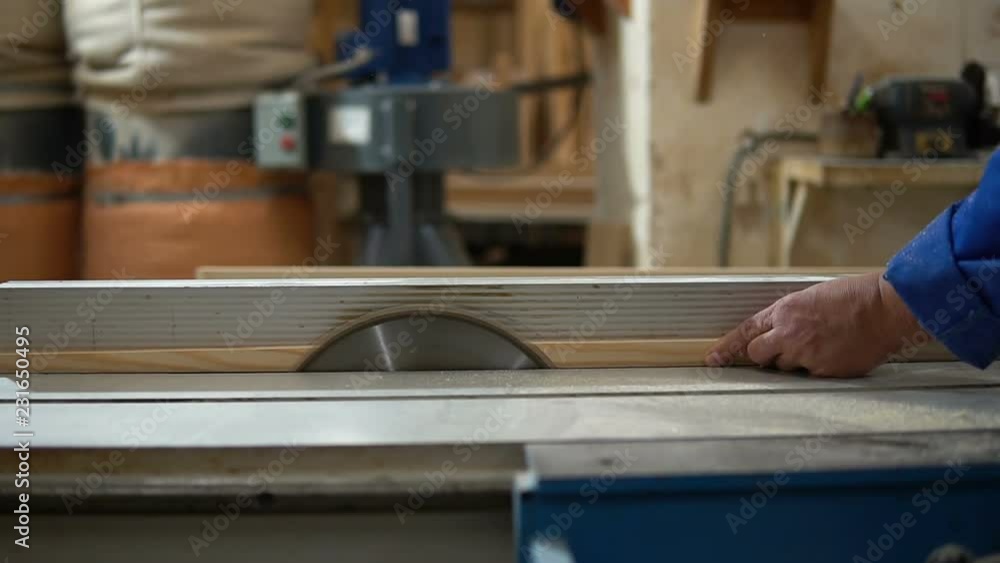 Carpenter at work at his workshop, wood processing on a woodworking machine Carpenter at work at his workshop, wood processing on a woodworking machine