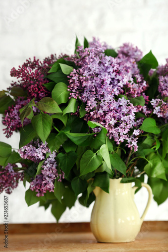 Lilac flower in a vase on a wooden background