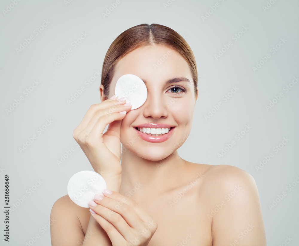 Cheerful woman removing face makeup with a cotton pad Cheerful woman removing face makeup with a cotton pad
