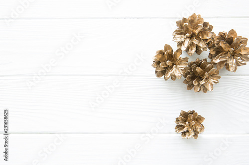 Golden pine cones on white wooden table background, top view, copy space.