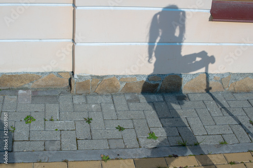 Gray shadow girls with pigtails. She stands near her scooter on background of wall